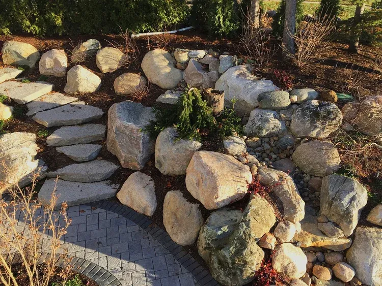 Stone retaining wall with large rocks beside a curved paved path in a garden
