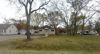 Suburban homes with leafless trees and a grassy front yard on an overcast day