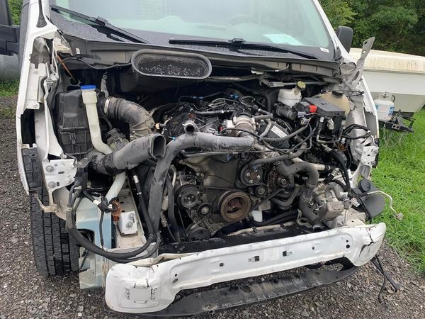 the engine of a white van is visible under the hood .