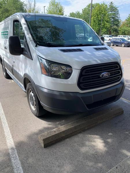 a white van is parked on a curb in a parking lot .