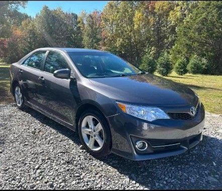 a gray toyota camry is parked on a gravel road .