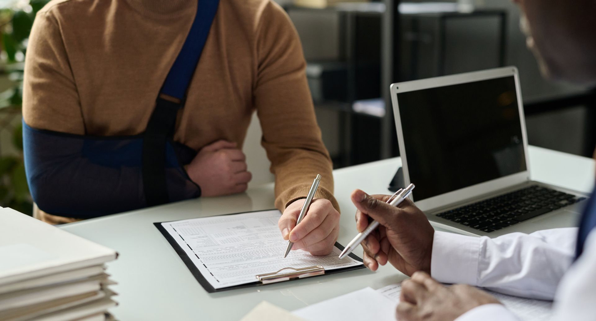 A man with a broken arm is sitting at a table with a personal injury lawyer
