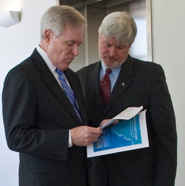 Two men in suits and ties are looking at a piece of paper