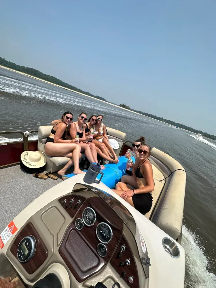 Group of people riding on a boat on a sunny day. They are smiling.