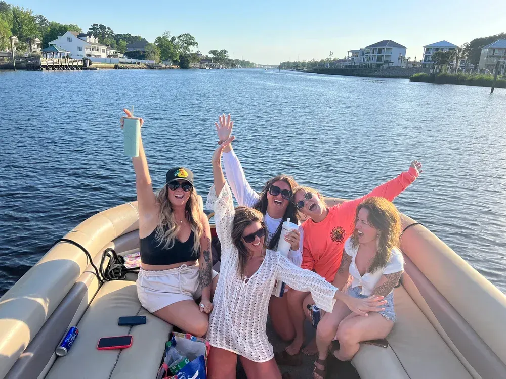 Group of people on a boat, waving and smiling on a waterway.