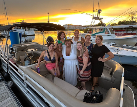 A group of people on a pontoon boat on a sunny day. They are smiling and enjoying the water.