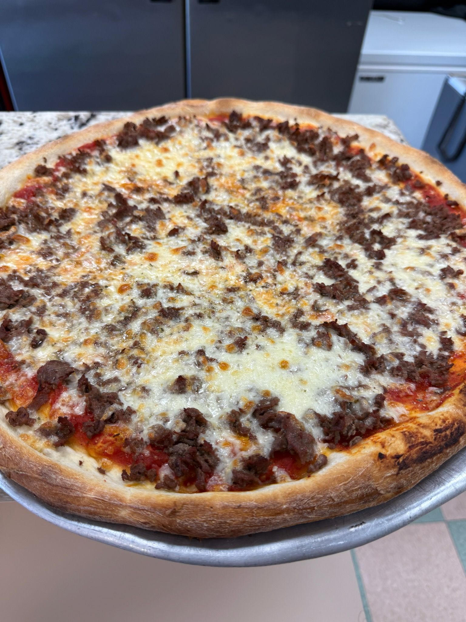 Cheese and pepperoni pizza on a metal tray with a golden-brown crust