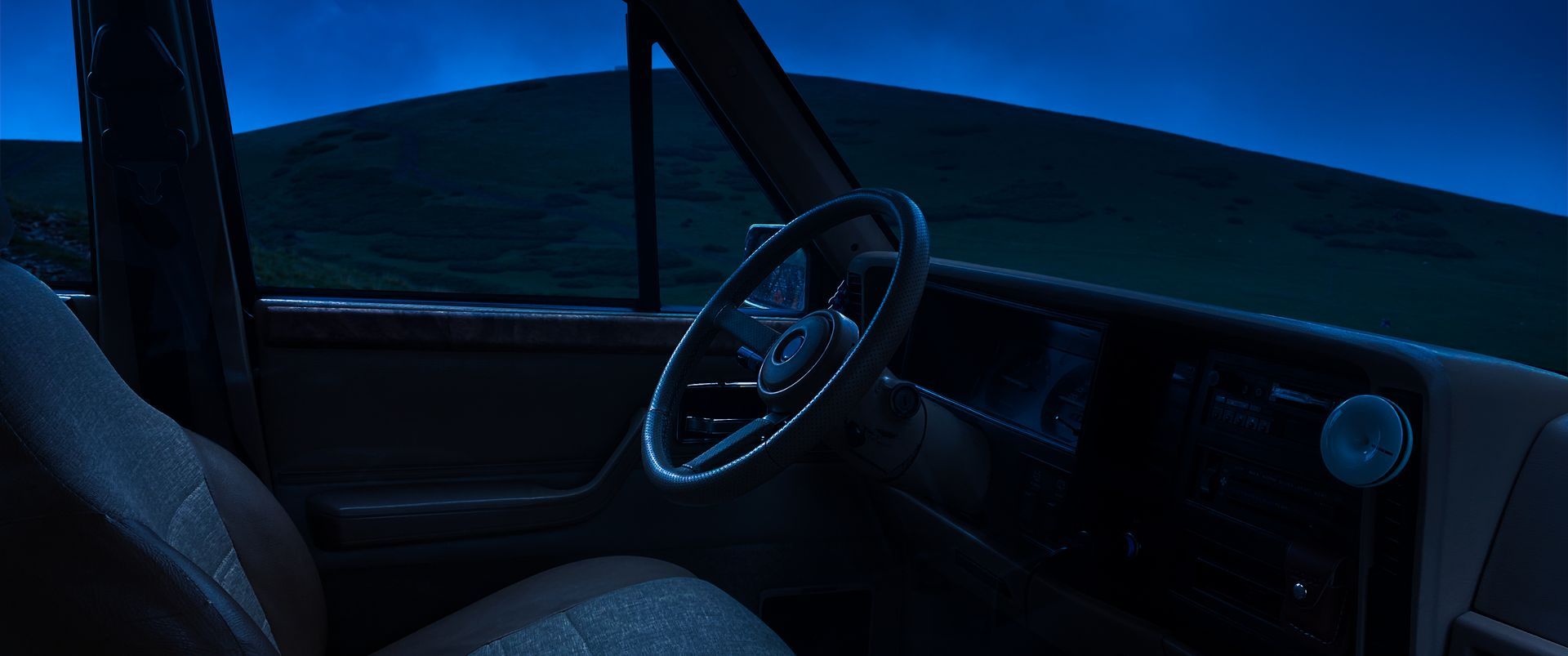 the inside of a car at night with the steering wheel visible