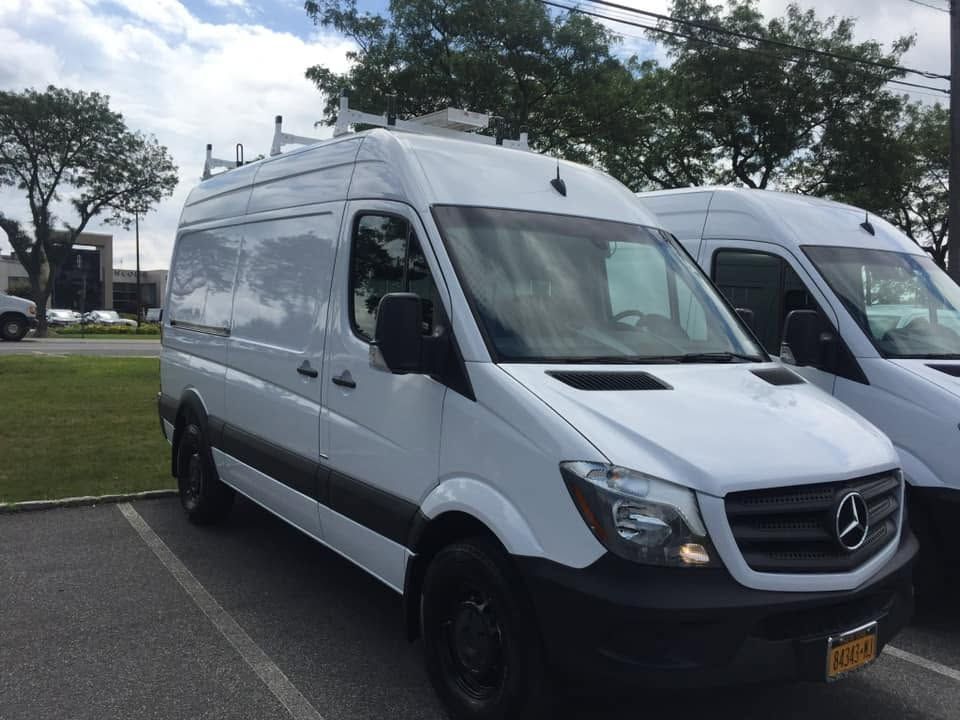 White Mercedes cargo van parked in a lot on a cloudy day