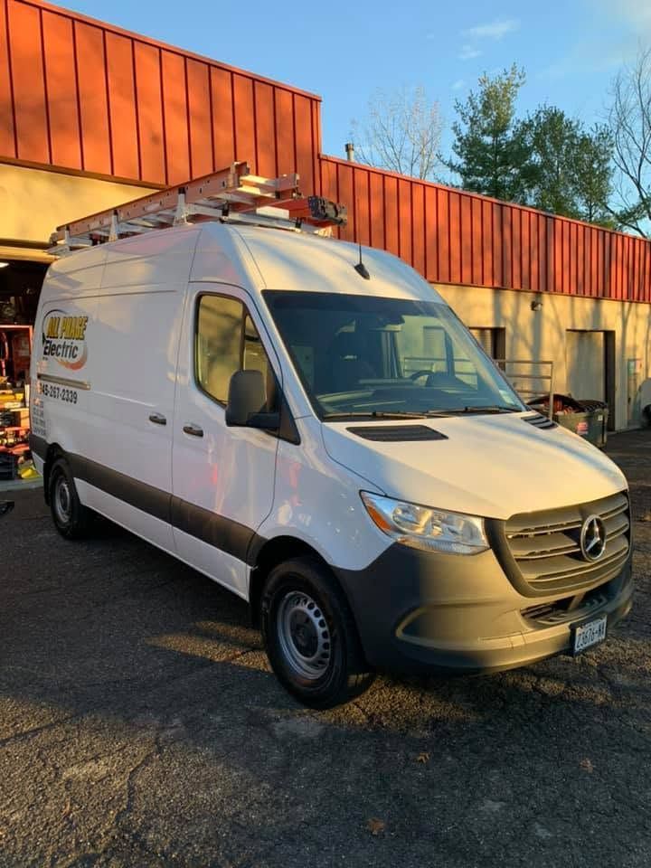 White Mercedes service van parked outside a building in warm sunlight