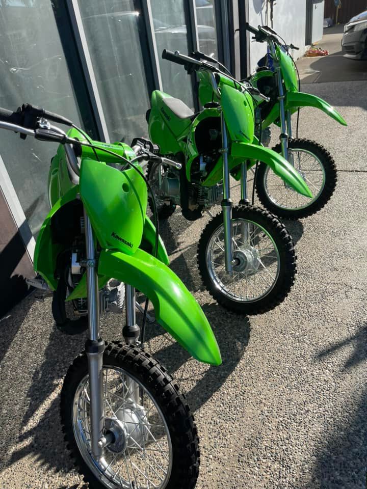 Three Green Dirt Bikes Are Parked in Front of a Building — Mackay Kawasaki in Cairns, QLD
