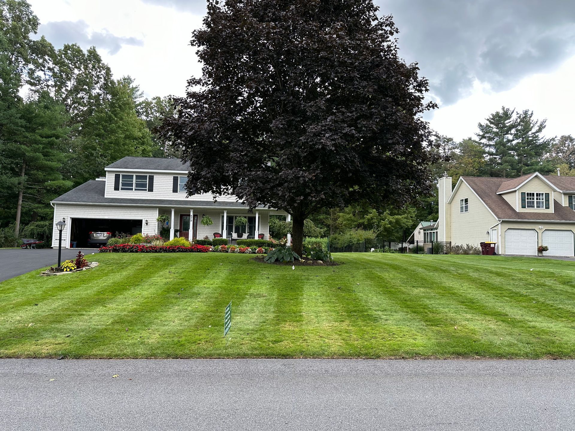 A house with a lush green lawn and a tree in front of it.