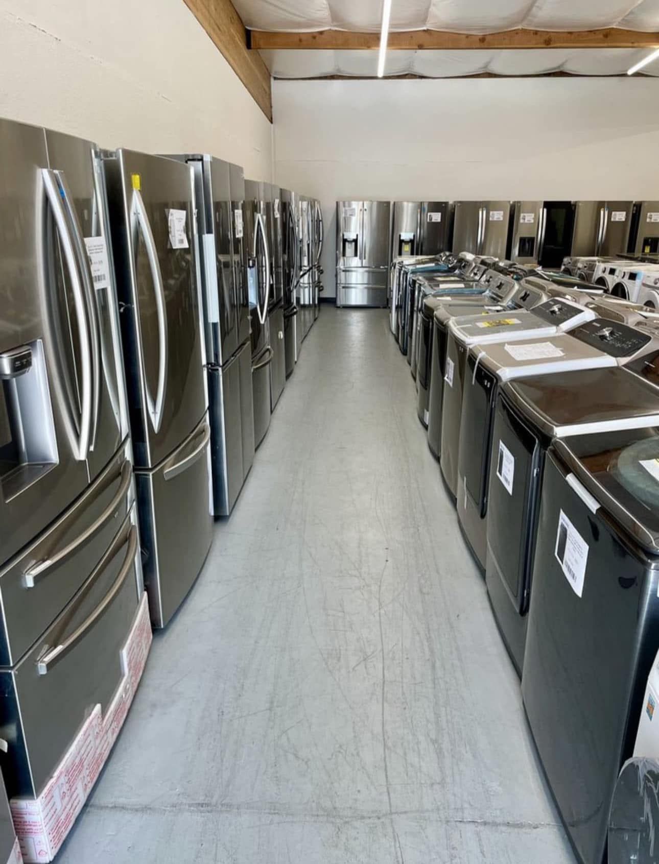 A row of refrigerators and washers are lined up in a store.
