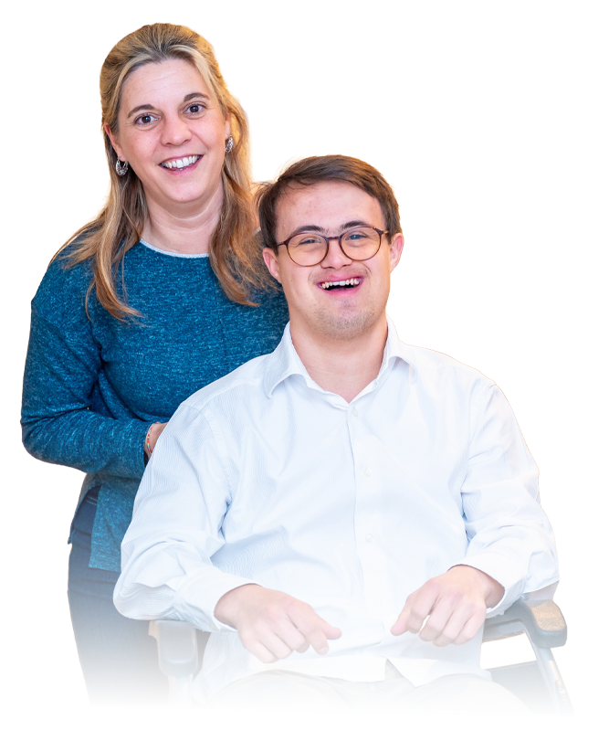 Two smiling people, one with a disability, seated in a white shirt and a support worker standing behind in a blue top, on a white background