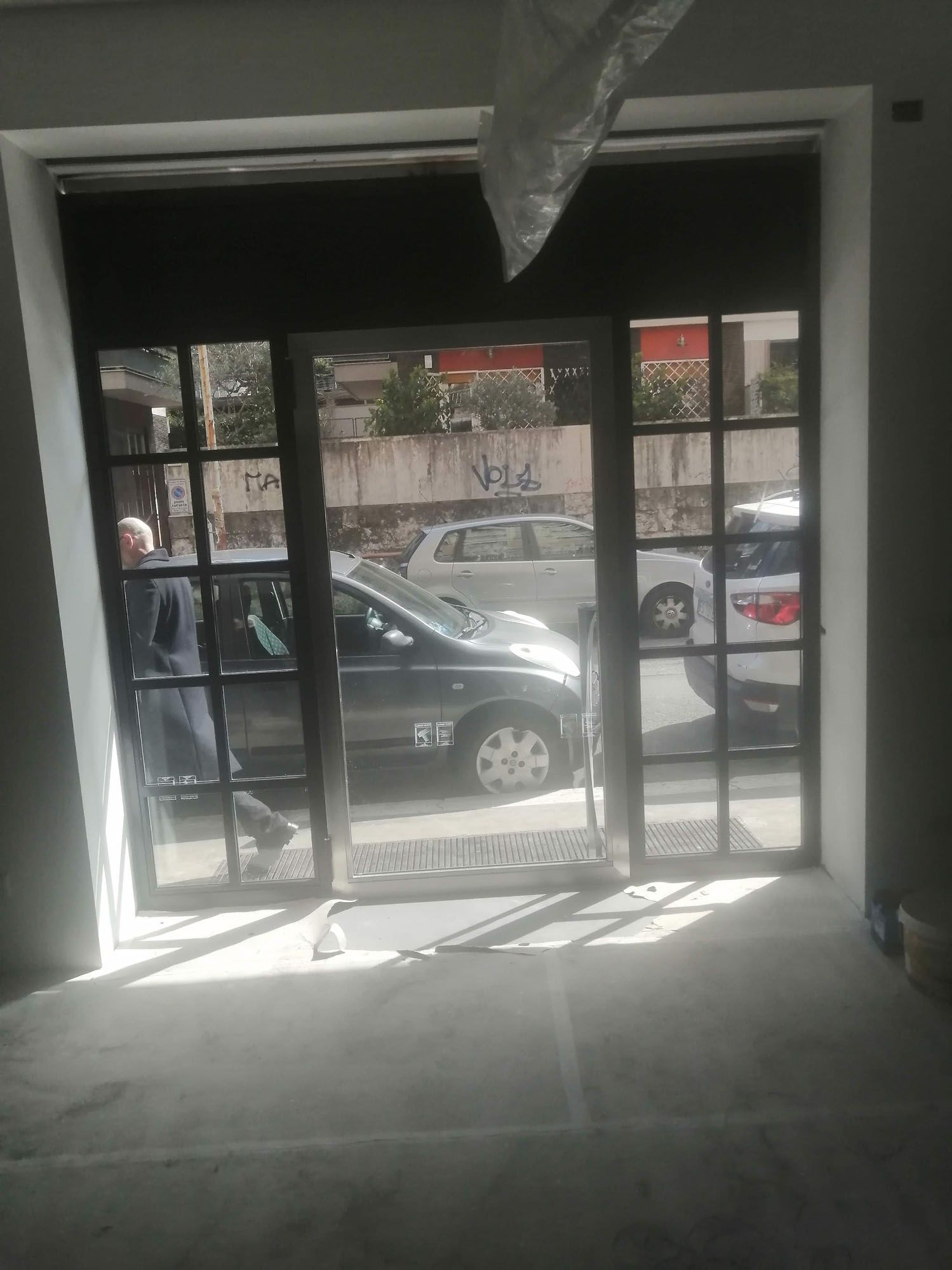 Vetrina di un negozio con auto visibili all'esterno; una persona è in piedi all'interno.