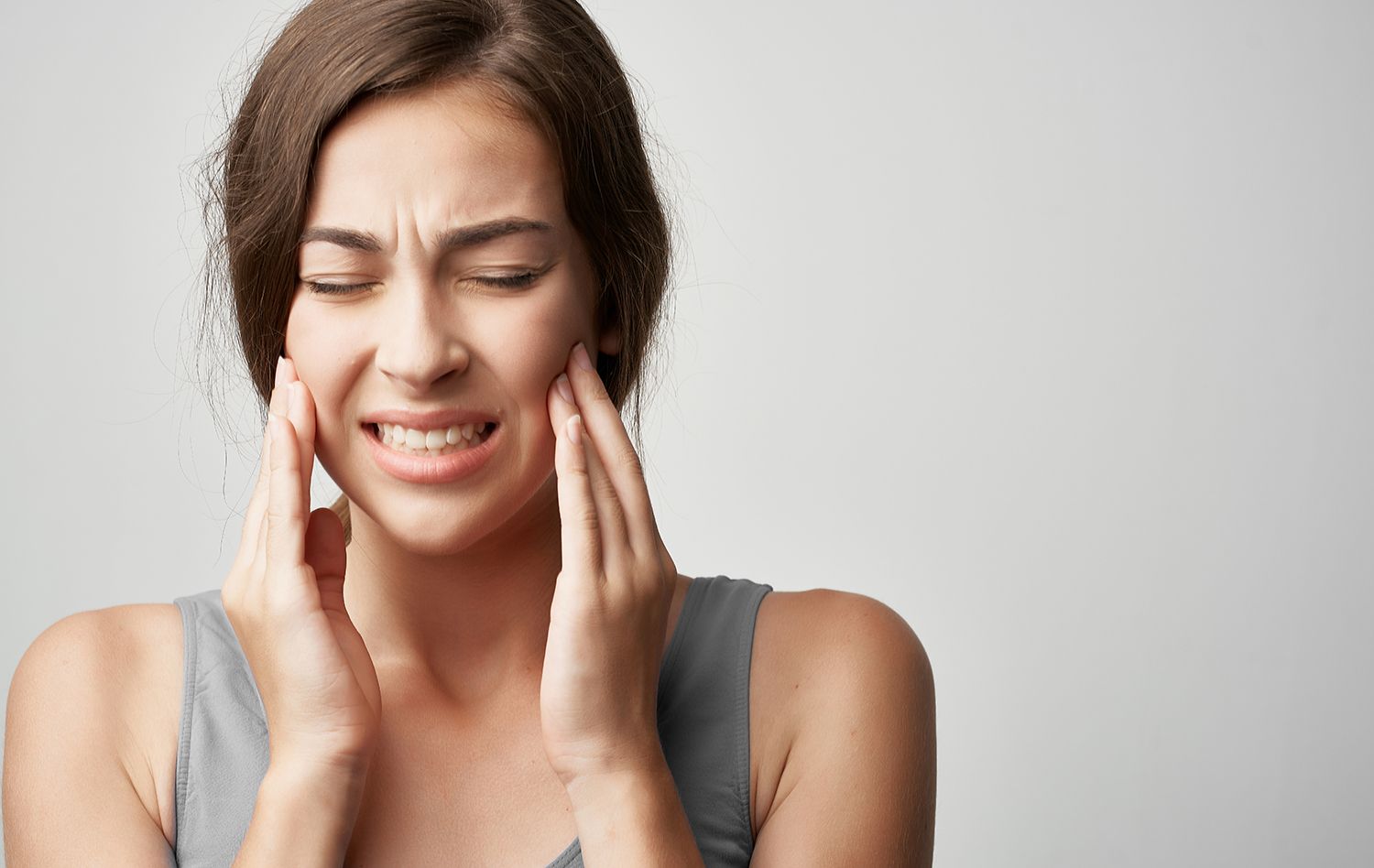 A woman is holding her face in pain because of a toothache.