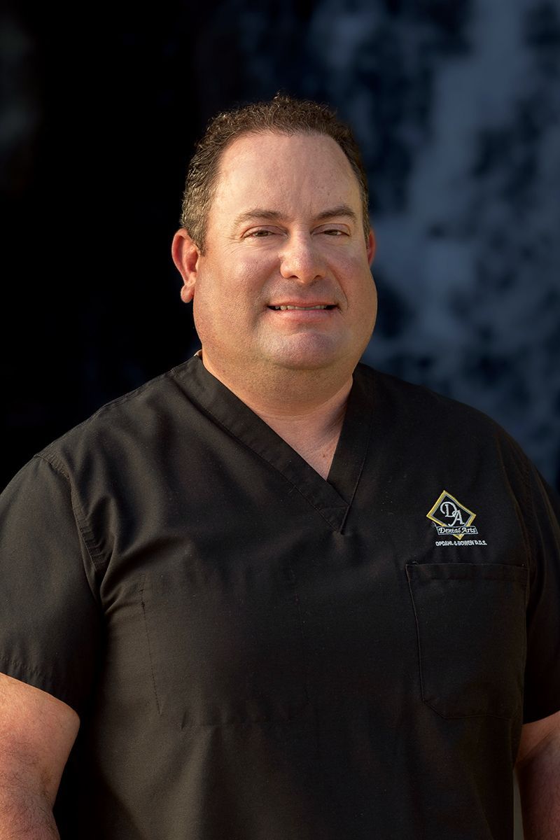 Dentist Dr. Bowen in a black scrub top is smiling for the camera.