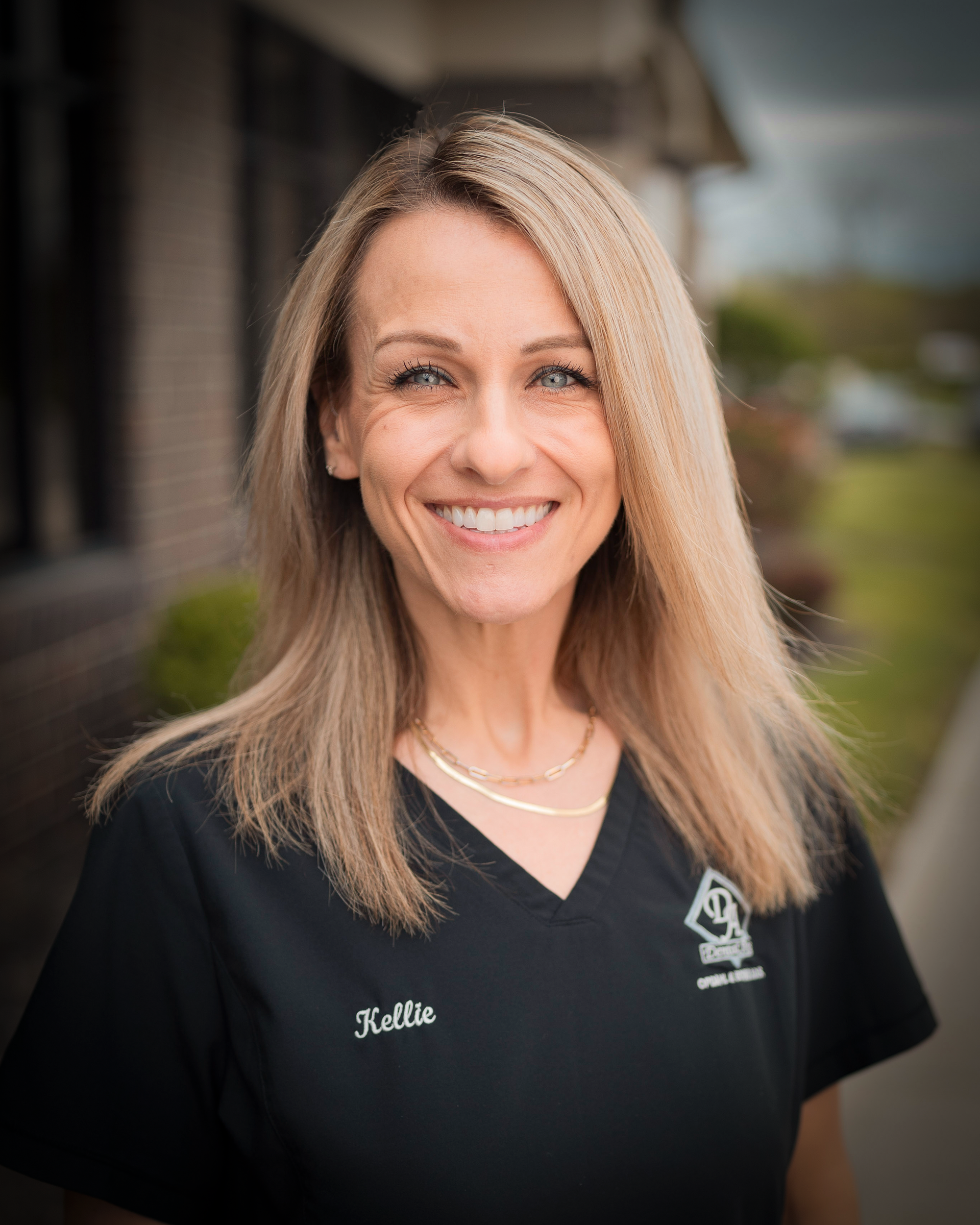 A woman in a black shirt is smiling for the camera.