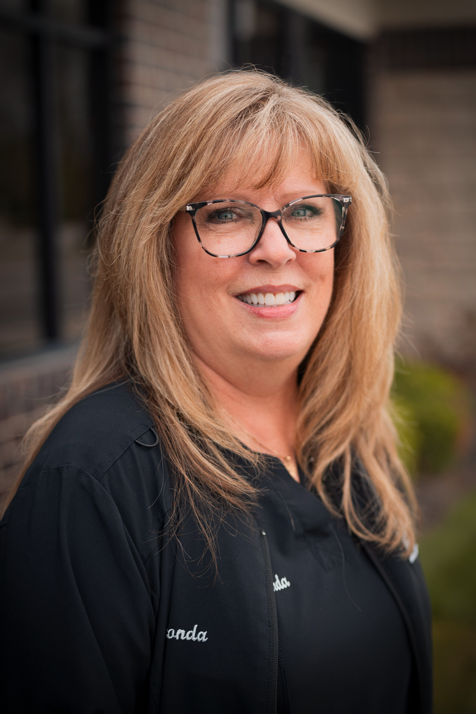 A woman in a black shirt is smiling for the camera.