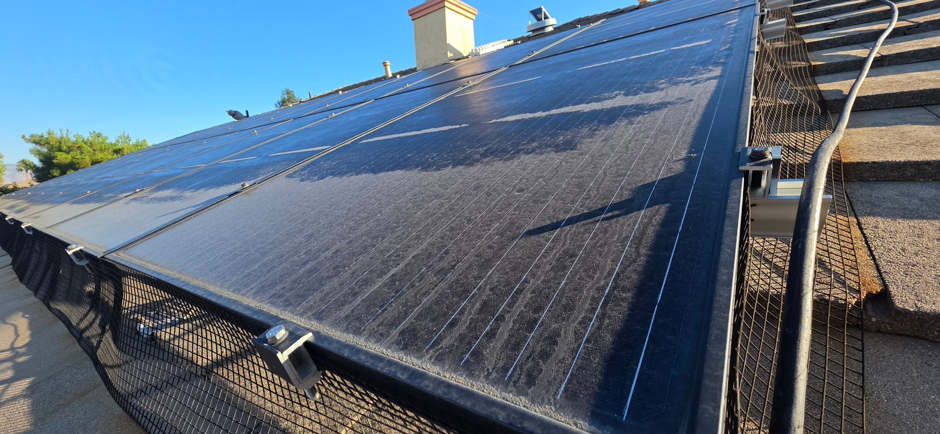 Solar panels mounted on a sloped roof under bright sunlight