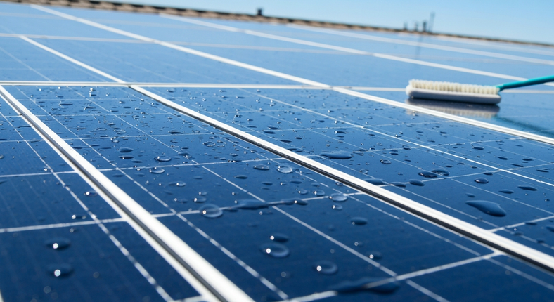 Blue solar panels covered with water droplets under a bright sky
