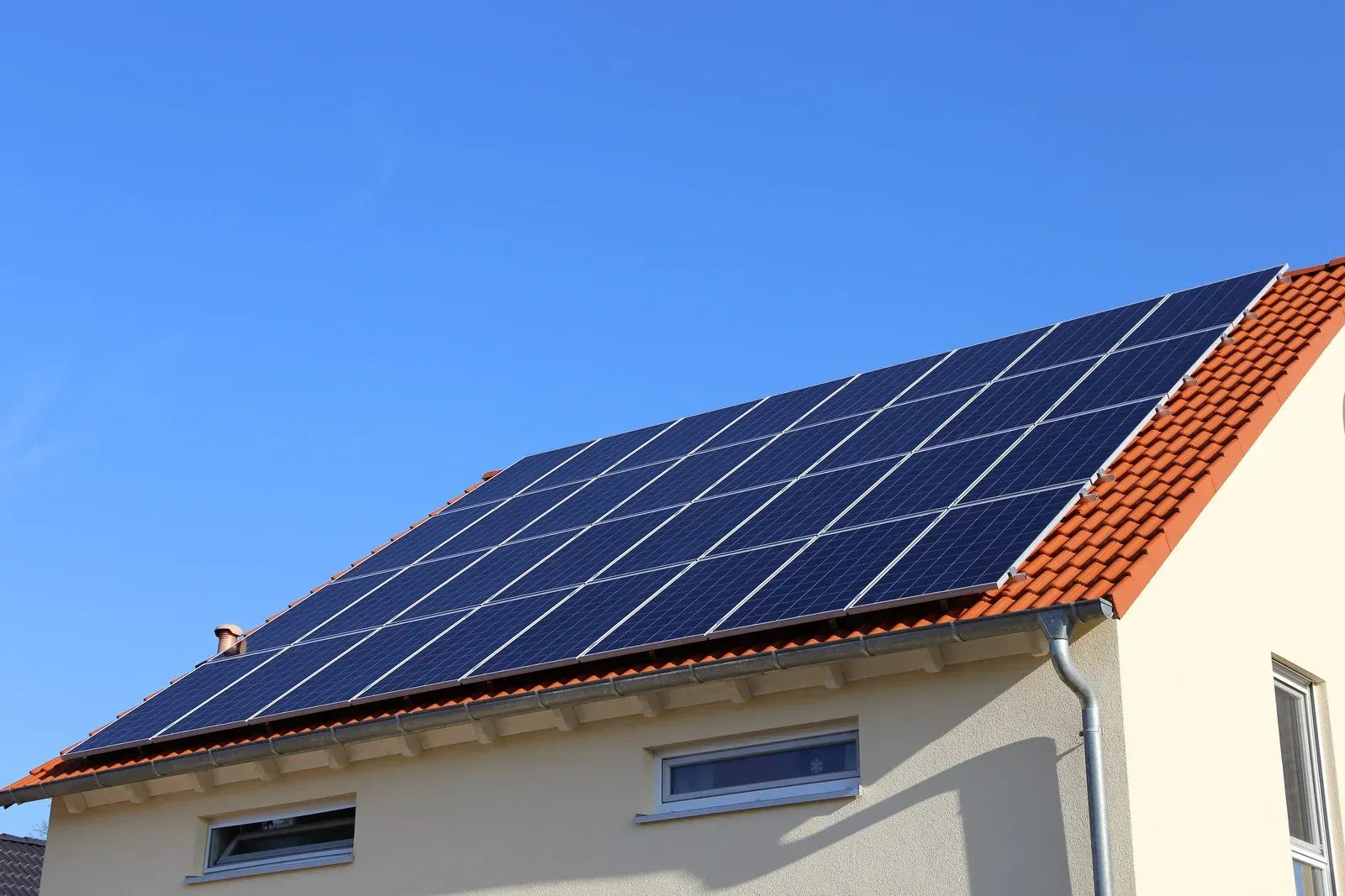 House roof with solar panels against a clear blue sky