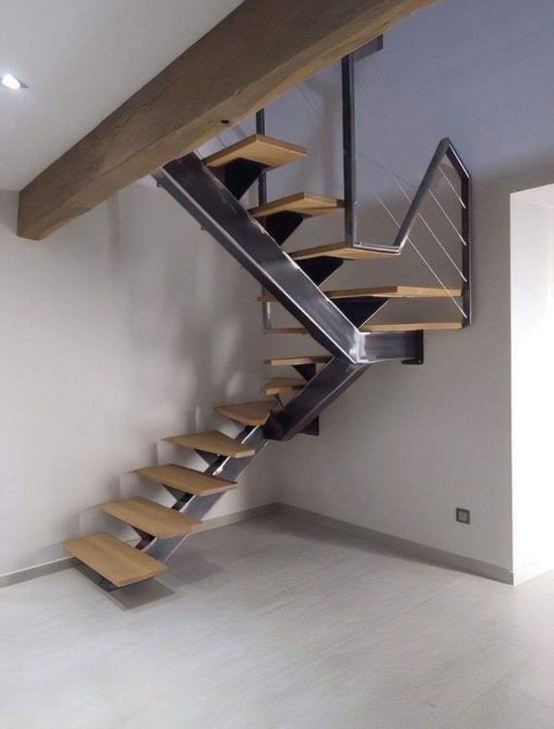 Escalier moderne avec marches en bois et structure en métal contre des murs blancs.