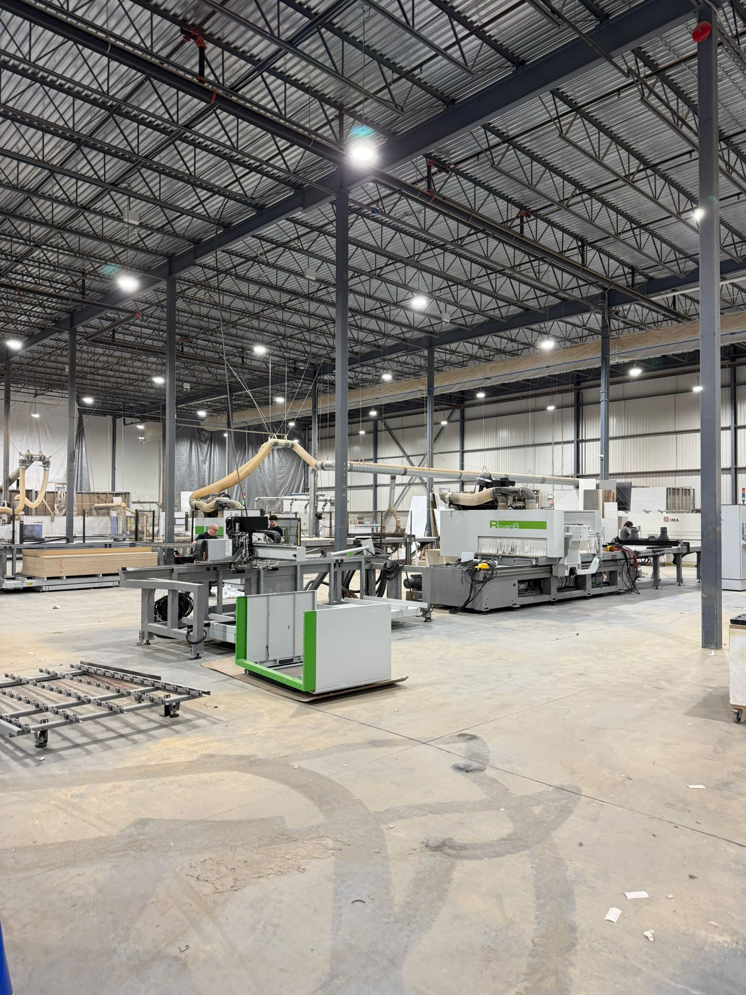 Intérieur d'un grand entrepôt avec des machines industrielles, de hauts plafonds et des plafonniers lumineux.