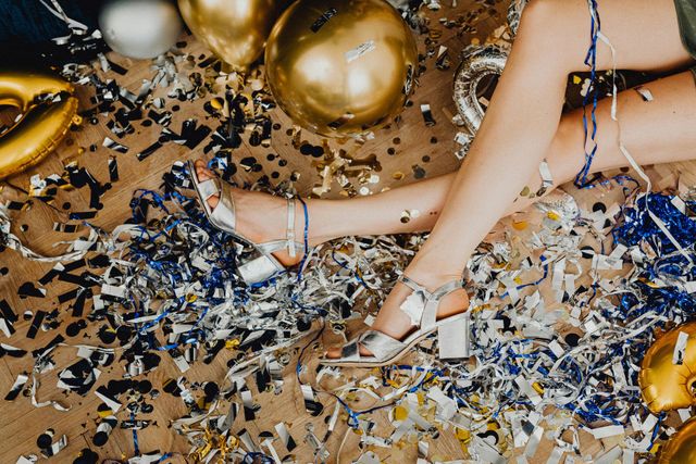 Legs among gold balloons and confetti, with hands and bracelets in a party scene