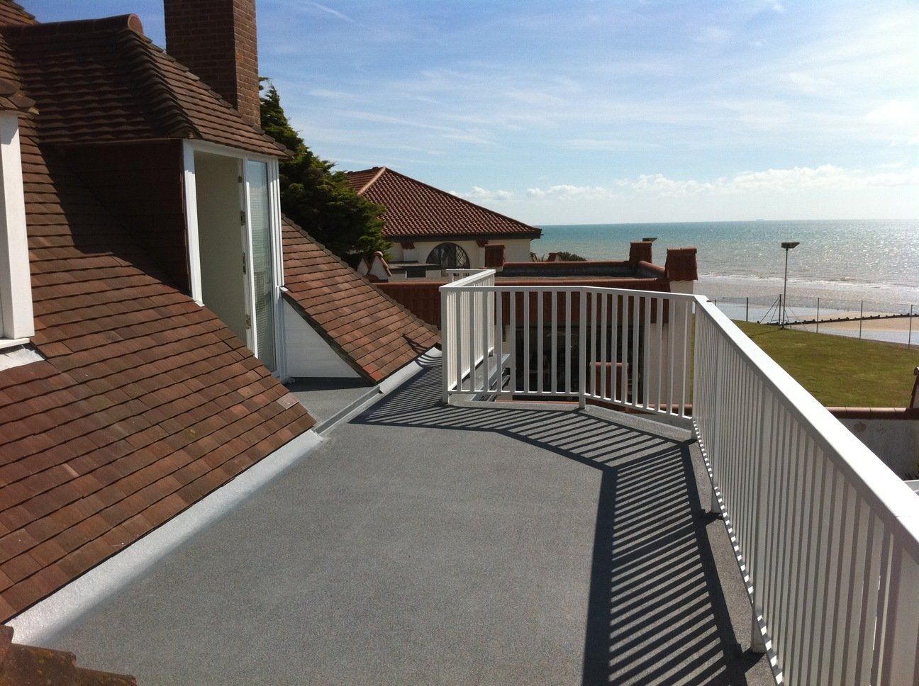 A balcony overlooking the ocean with a white railing