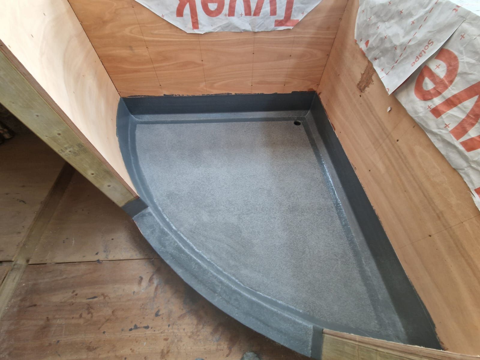 A corner of a room with a concrete floor and a wooden wall.