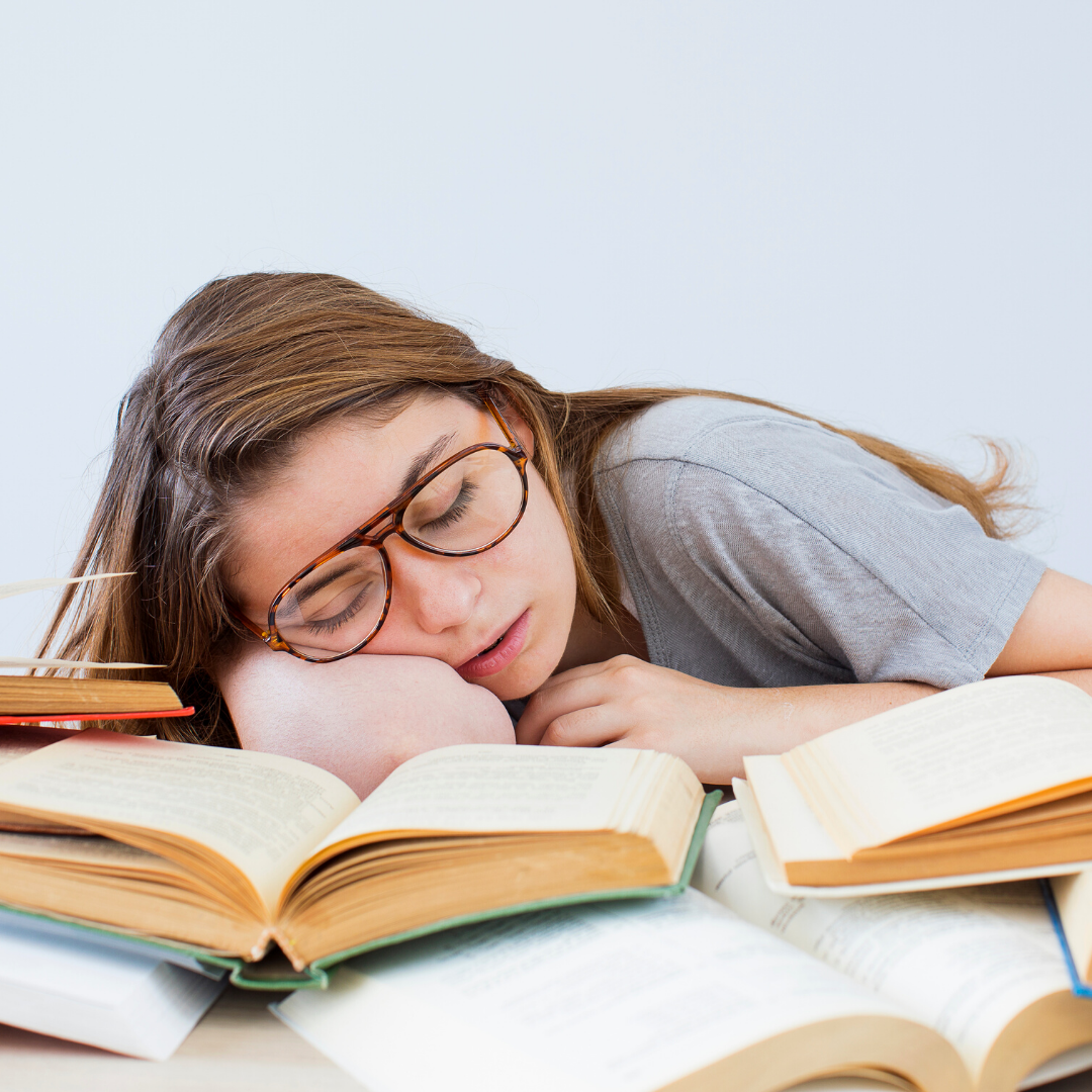 Jovem dormindo sobre os livros