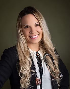 Portrait of a smiling woman in a black blazer and stethoscope against a dark background