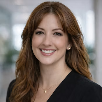 Smiling professional in a black top, posed against a softly blurred office background