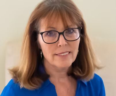 Portrait of a woman wearing glasses and a blue blouse against a plain background