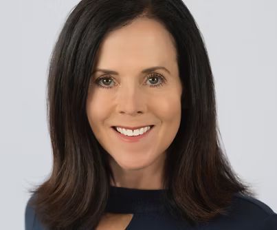 Smiling woman with dark shoulder-length hair against a light gray background