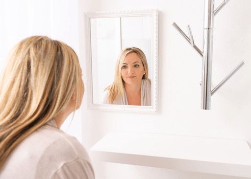Eine Frau betrachtet ihr Spiegelbild.