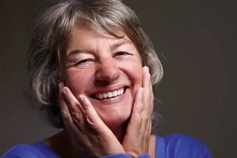 Smiling Older Woman With Hands on Cheeks; Grey Hair, Blue Top — Smiles on Hudson In Hamilton, NSW