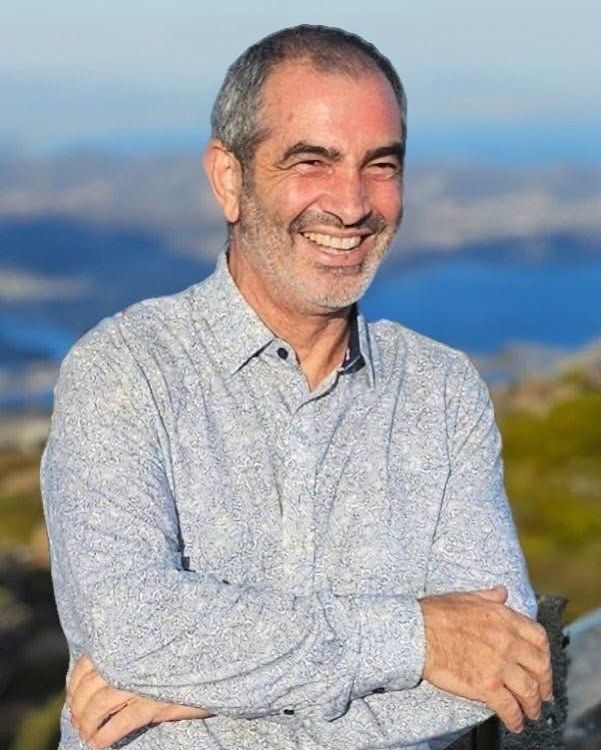 Man with graying hair smiling, arms crossed, outdoors with mountains in background — Smiles on Hudson In Hamilton, NSW