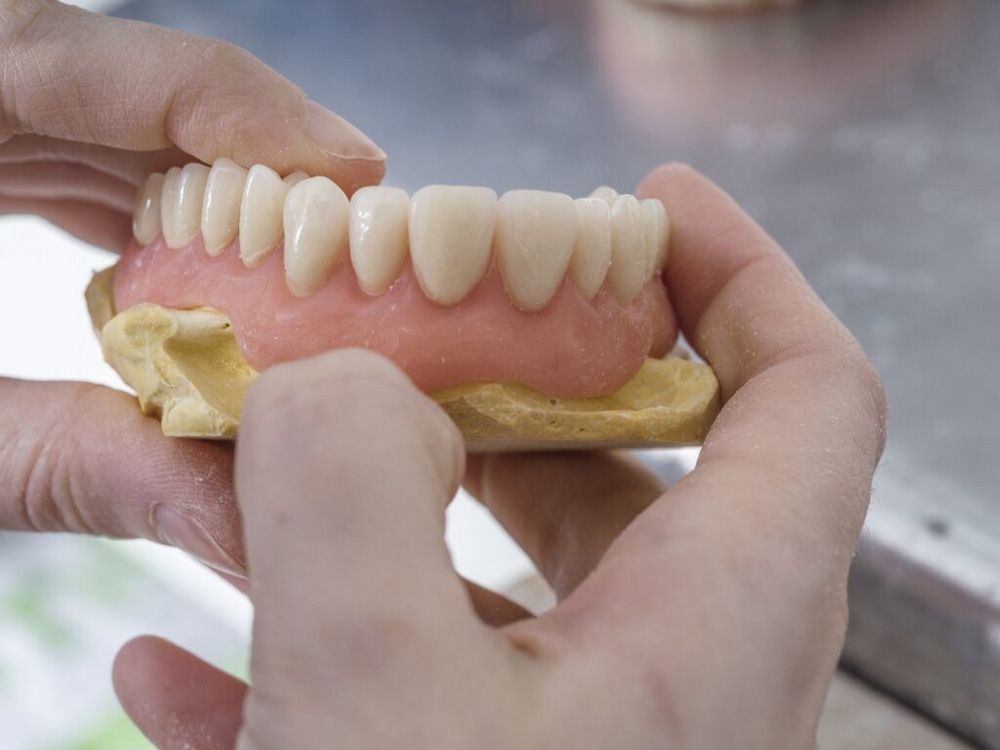 Hands Holding a Set of Dentures — Smiles on Hudson In Lake Macquarie, NSW