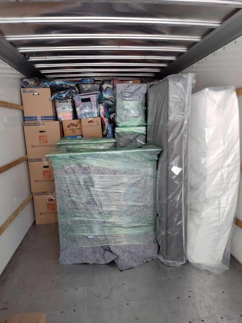 The inside of a moving truck filled with boxes and mattresses.