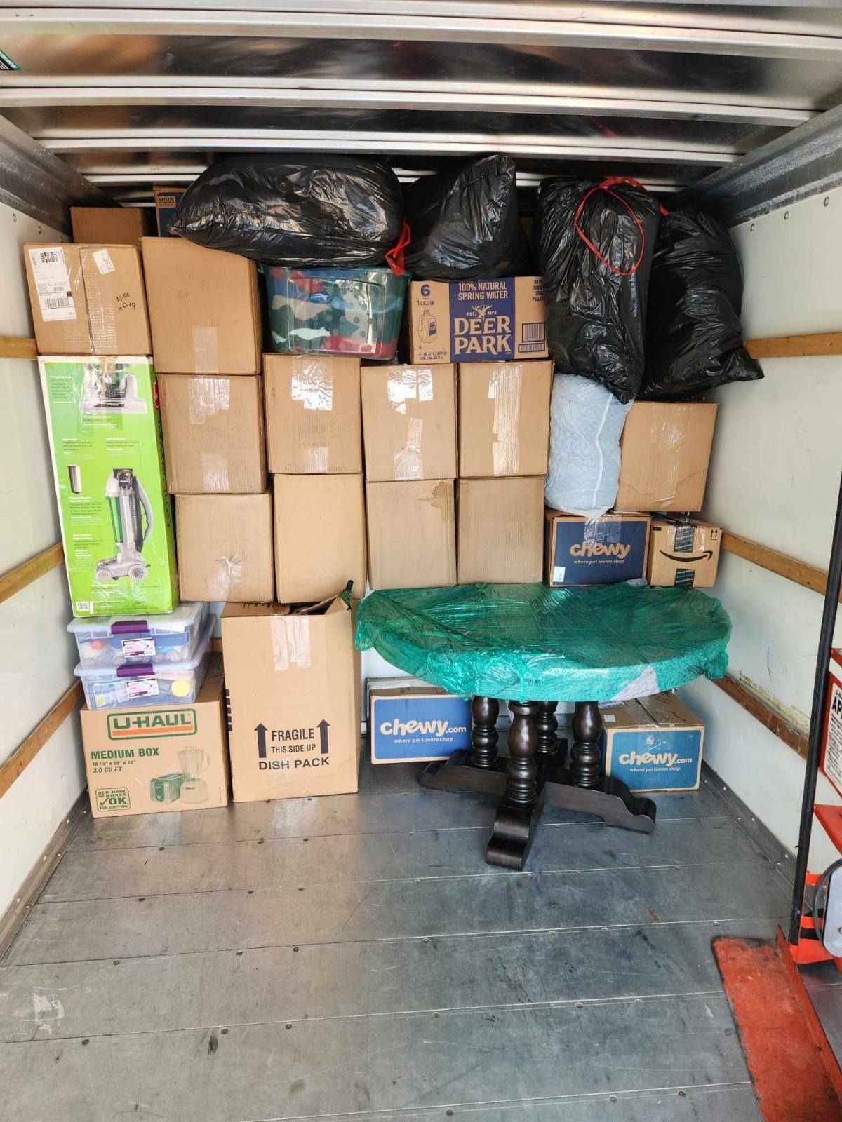 The inside of a moving truck filled with boxes and a table.
