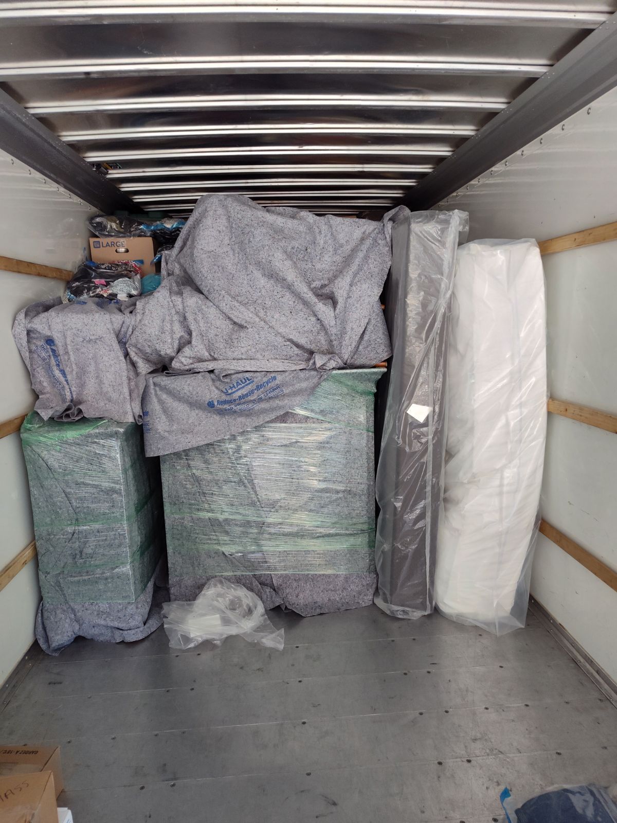 The inside of a moving truck filled with boxes and mattresses.