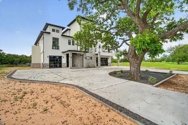 Modern house with stone facade, two levels, balconies, and a pool. Spiral staircase on the side.