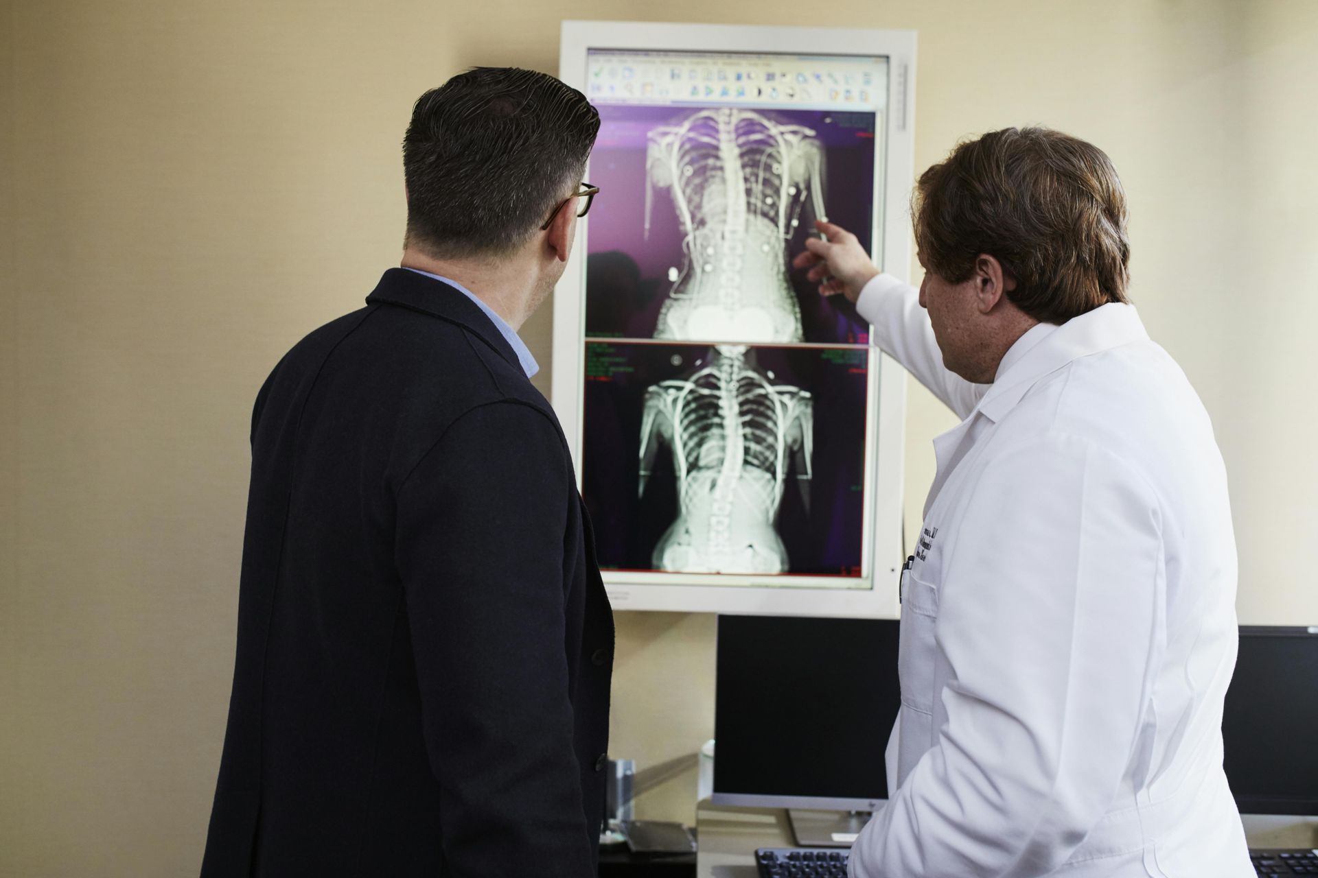 Two men are looking at an x-ray of a person 's back