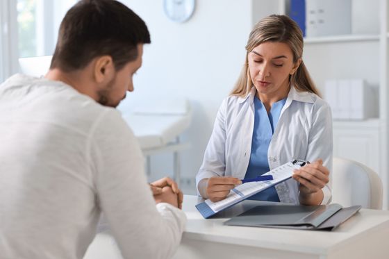 A doctor is talking to a patient at a desk in a hospital.