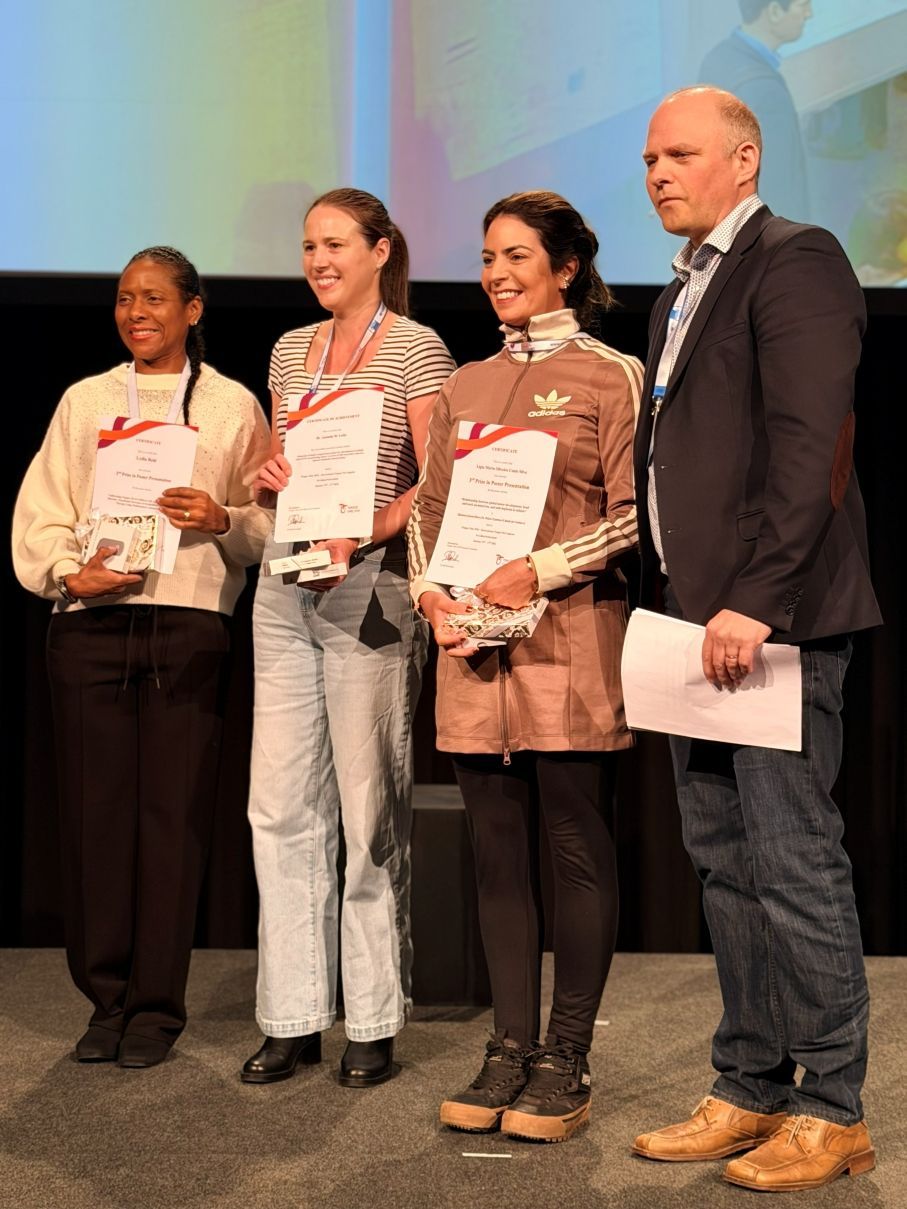Four people onstage holding certificates and posing for a photo at an awards ceremony.