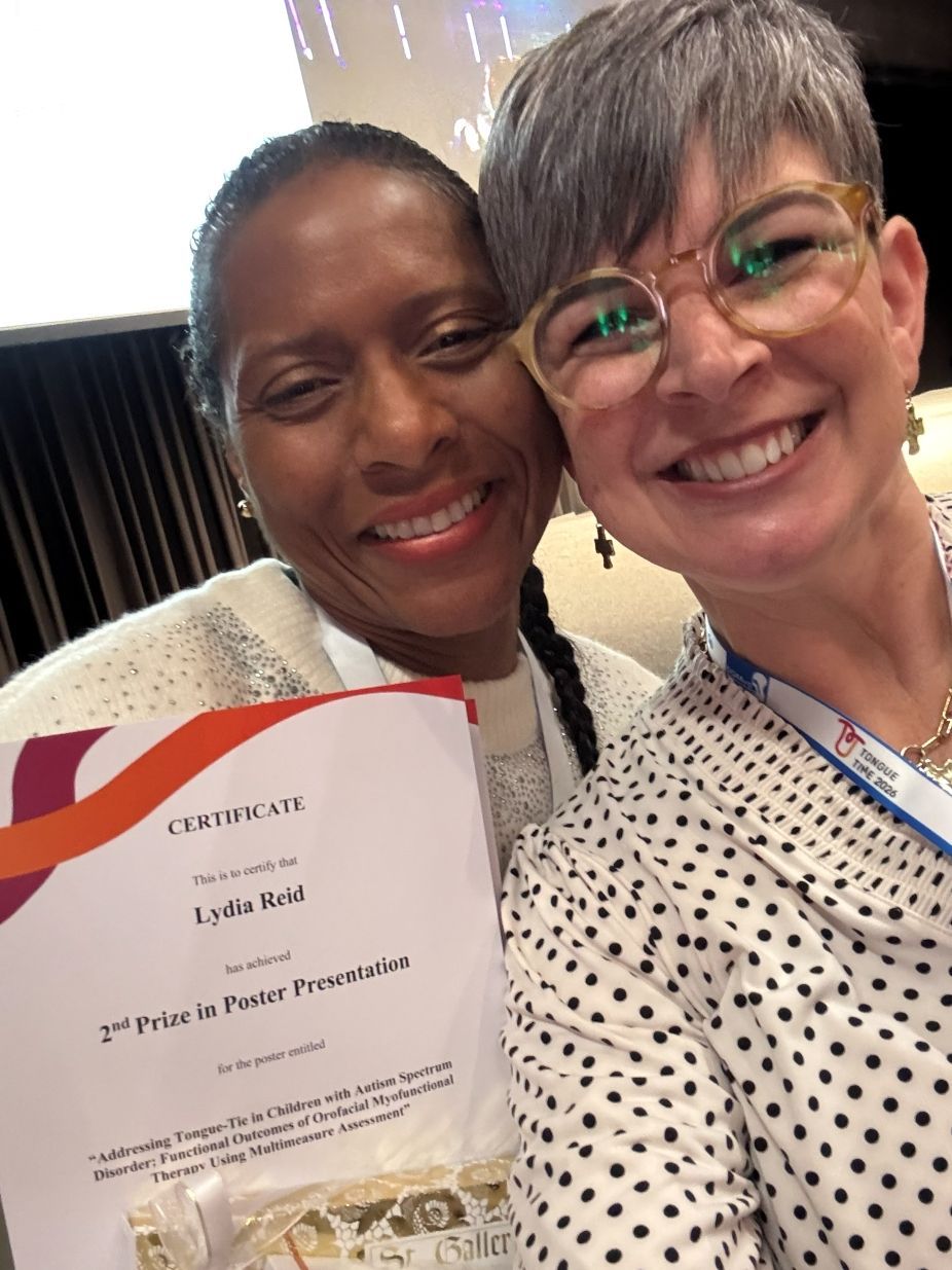 Two smiling people holding a certificate at a formal event.