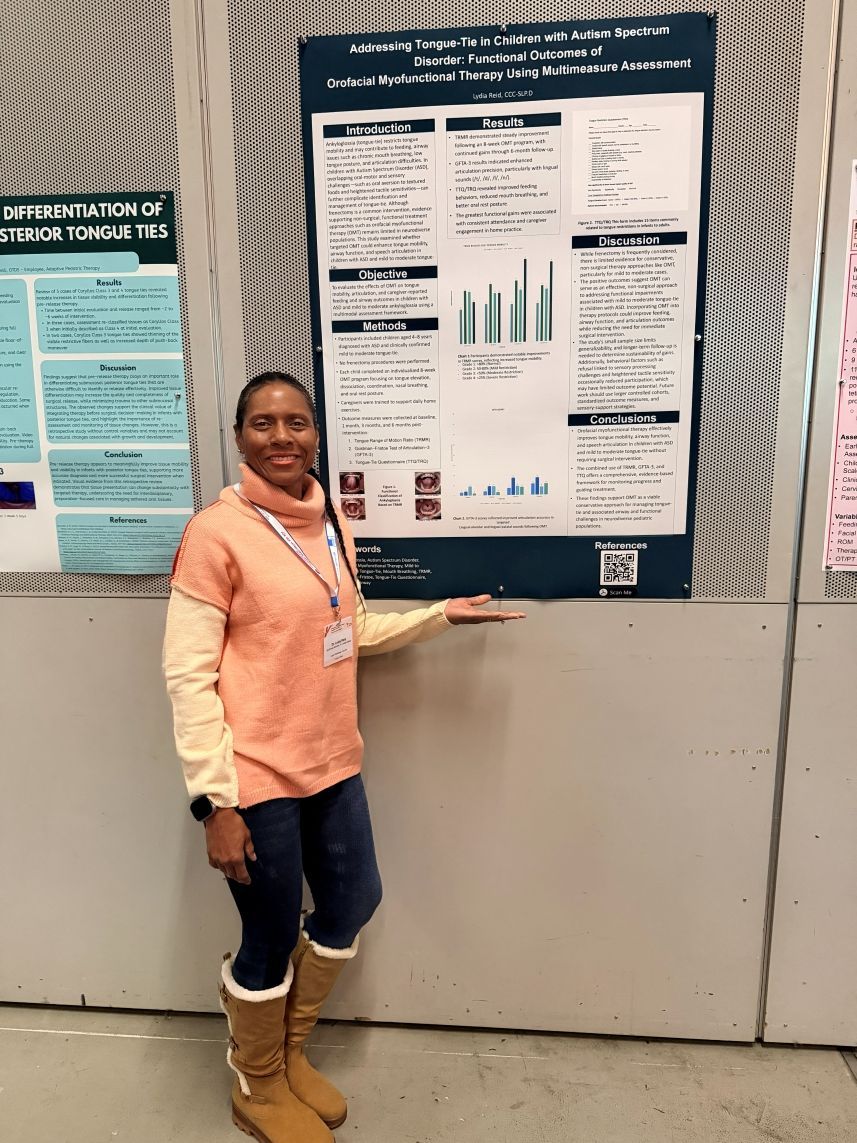 Woman smiling beside a research poster at a conference display.
