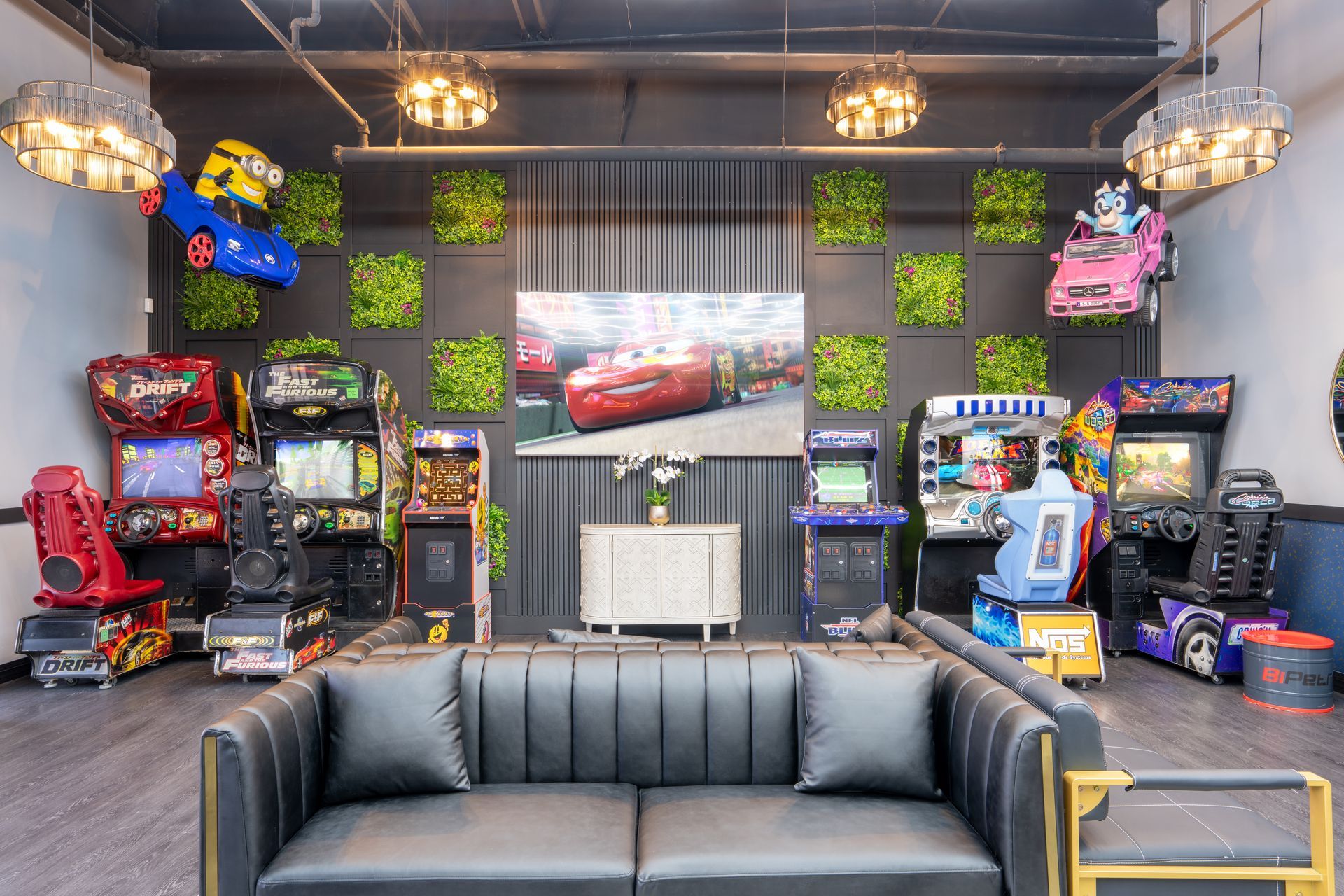 Arcade room with black leather sofa, racing game cabinets, neon lights, and car-themed wall art